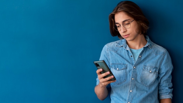 Foto gratuita ritratto di un bel ragazzo adolescente che controlla il suo telefono