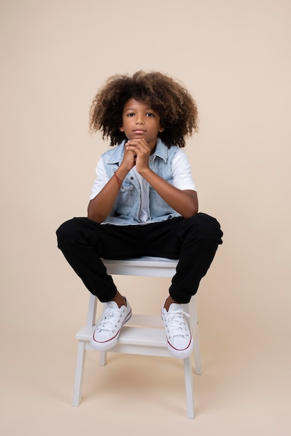 Free photo portrait of cool teenage boy posing on chair