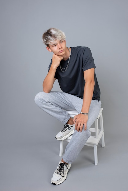 Free photo portrait of cool teenage boy posing on a chair