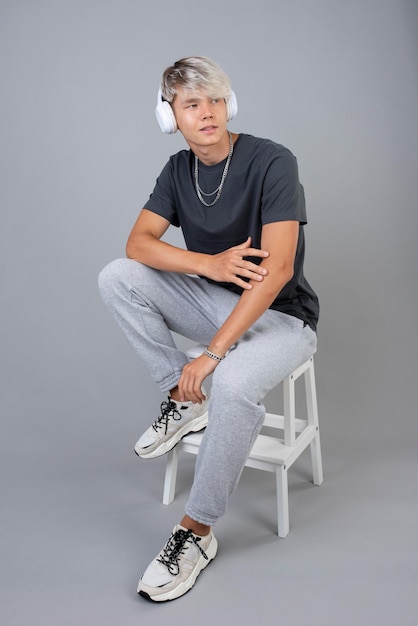 Portrait of cool teenage boy with headphones posing on a chair