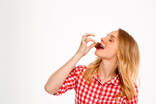 Ritratto della donna del paese con la fragola su bianco.