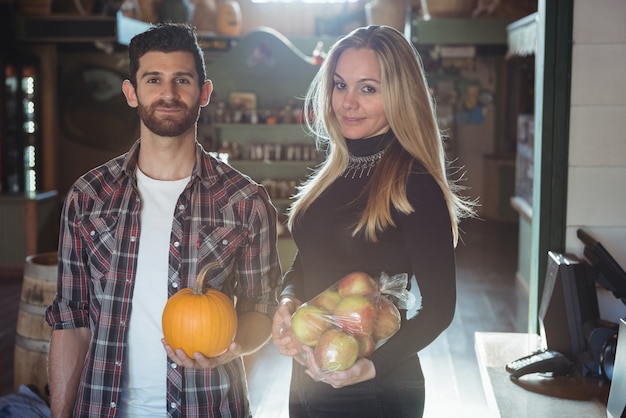 Portrait of couple holding vegetable and fruits