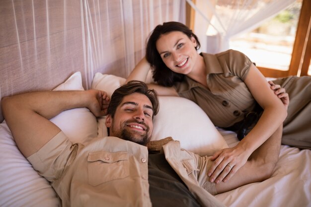 Портрет пара, улыбаясь лежа на кровати с балдахином