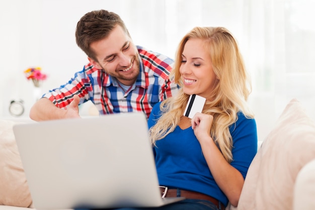 Портрет пары с ноутбуком и кредитной картой в гостиной
