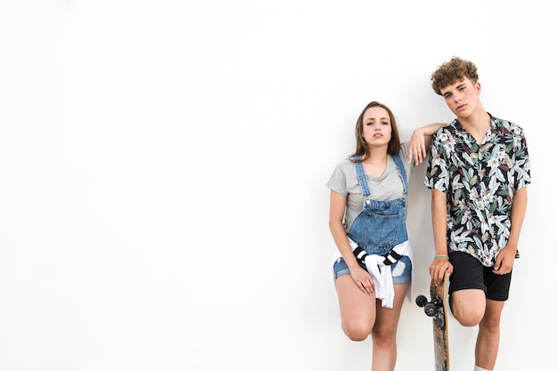 Портрет пара с скейтбордом, стоя на белом фоне
