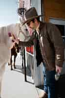 Free photo portrait of cowboy brushing white horse