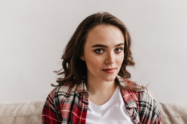 Portrait of curly brunette woman in light living room