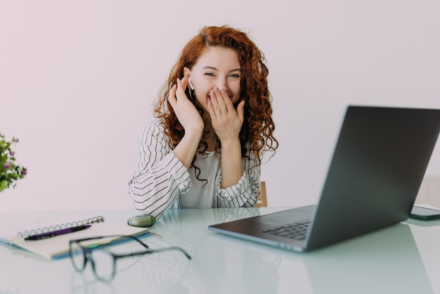 Portrait of curly young businesswoman in a headset holding the microphone attentive customer service representative responding to customer inquiry Female employee in headphones talking