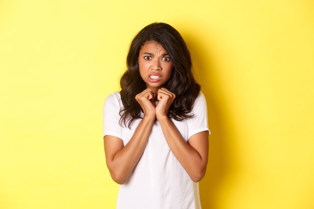 Portrait of cute africanamerican girl looking scared and reluctant grimacing displeased standing