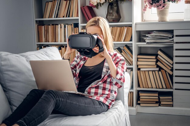 Portrait of cute blonde female using smartphone and virtual reality glasses.