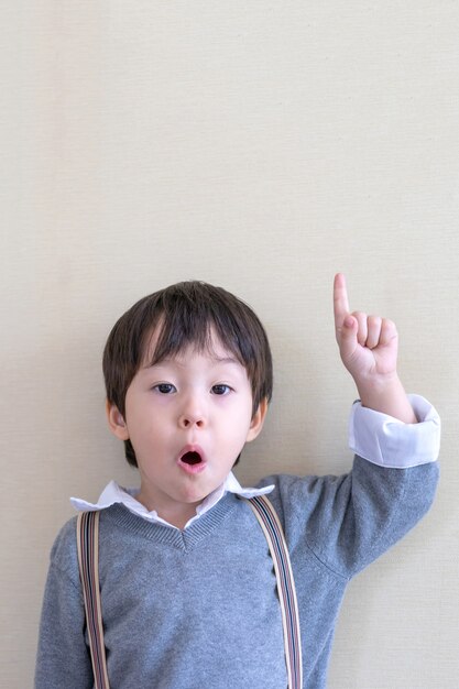 Portrait cute boy finger-pointing upward on white