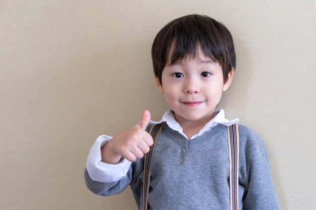 Portrait cute boy standing and thump up 