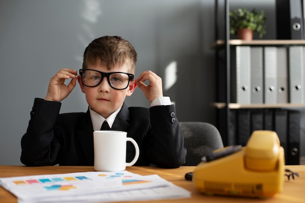 Free photo portrait of cute boy working at his office desk