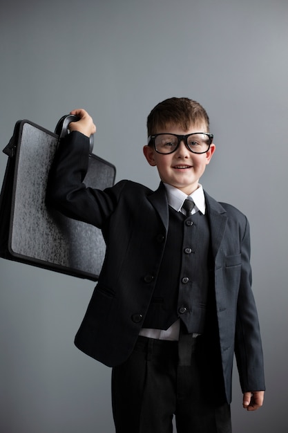 Free photo portrait of cute child with suit and briefcase