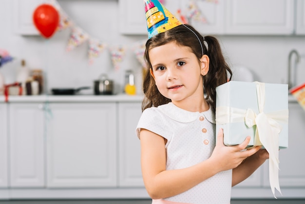 Портрет милая девушка держит подарок на день рождения в кухне