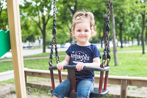 Free photo portrait of cute girl sitting in the swing