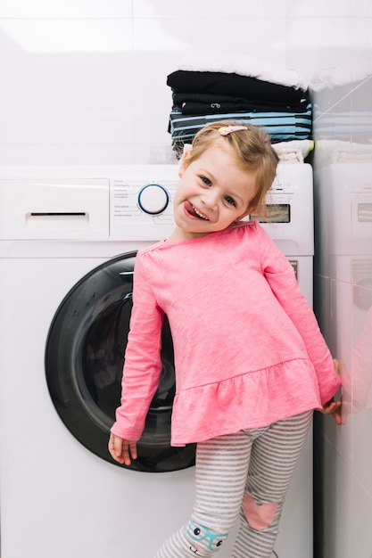 Ritratto di una ragazza carina in piedi davanti alla lavatrice