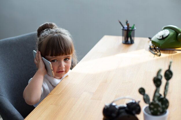 Free photo portrait of cute girl using smartphone at her office desk