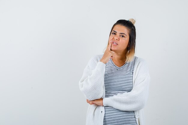 티셔츠, 카디건을 입고 사려깊은 앞모습을 보고 있는 귀여운 여성의 초상화