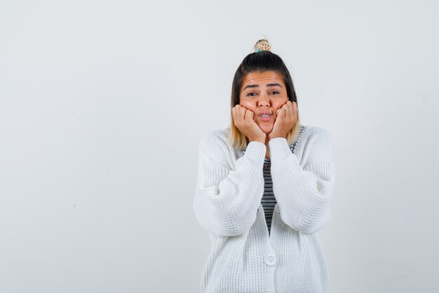 Free photo portrait of cute lady leaning cheeks on hands in t-shirt, cardigan and looking excited