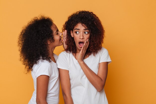 Portrait of a cute little african girl telling a secret