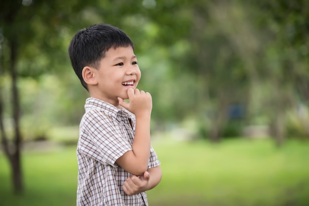 Portrait of cute little asian boy hand under chin And Thinking While Standing