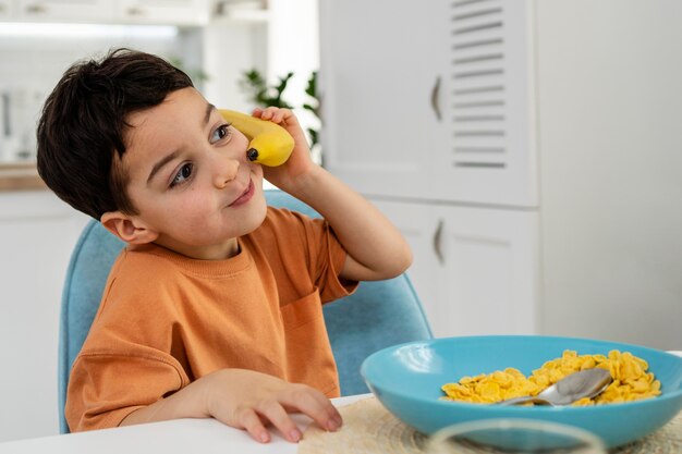 Portrait of cute little boy playing with banana