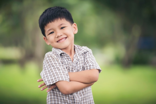 折り畳まれた、カメラを見ている腕で立っているかわいい少年の肖像