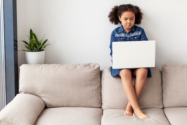 Free photo portrait of cute little girl holding laptop