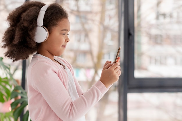 Free photo portrait of cute little girl listening to music