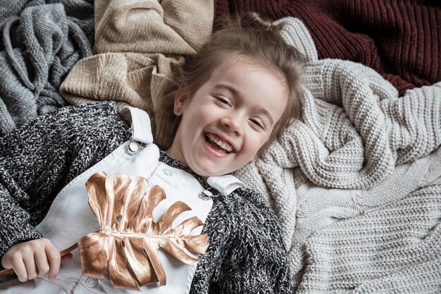 Portrait of a cute little girl in a sweater with a leaf in her hands.