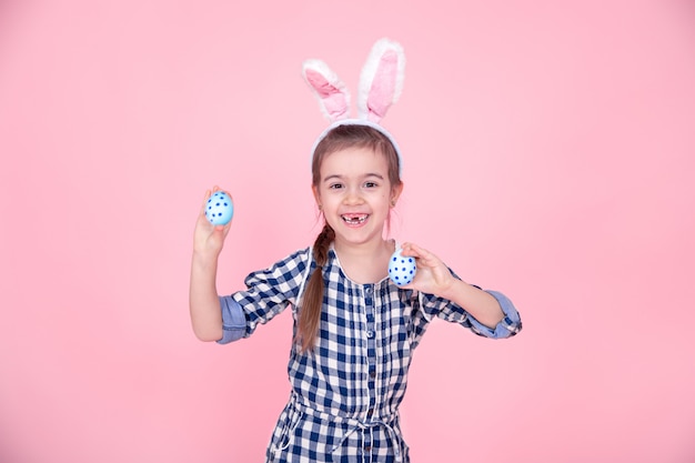 Ritratto di una ragazza carina con le uova di pasqua su uno sfondo rosa.