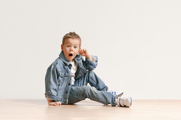 Il ritratto del ragazzo carino bambino in jeans eleganti vestiti guardando la fotocamera