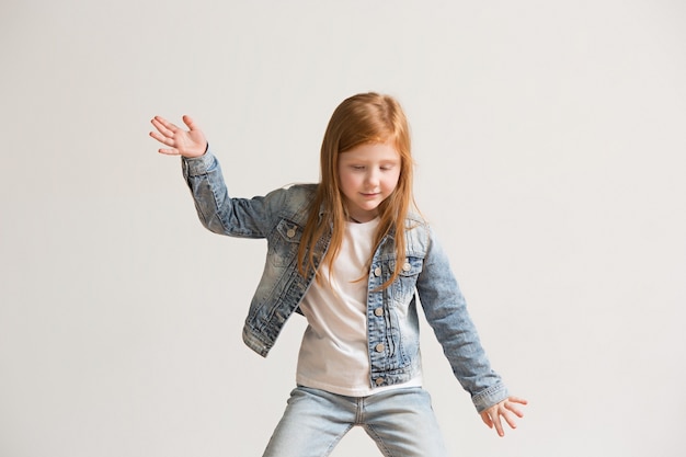 portrait of cute little kid in stylish jeans clothes looking at camera and smiling