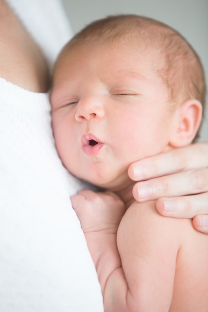 かわいい新生児の肖像画は、母親の乳房で保持する