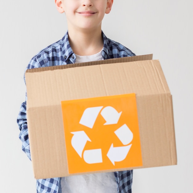 Portrait of cute young boy holding recycling box