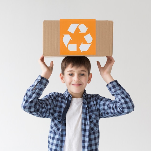 Portrait of cute young boy posing with recycle box