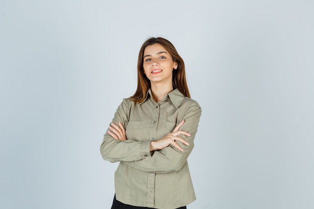 Foto gratuita ritratto di giovane donna carina che tiene le braccia conserte in camicia e guarda allegra vista frontale