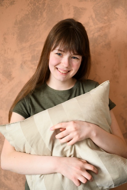 Портрет милой молодой девушки, держащей подушку