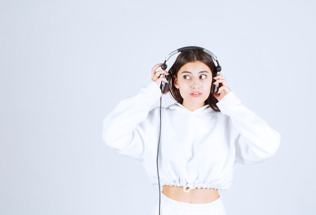 Portrait of a cute young girl model standing with headphones .