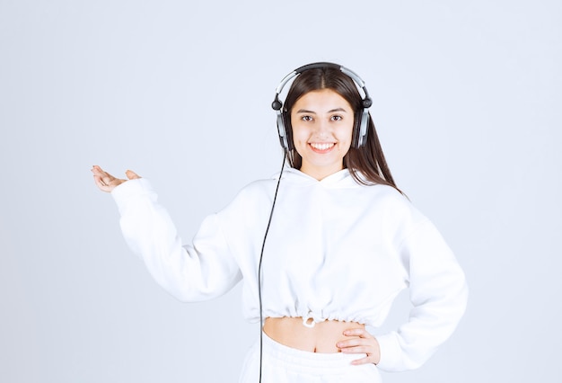 Portrait of a cute young girl model standing with headphones .