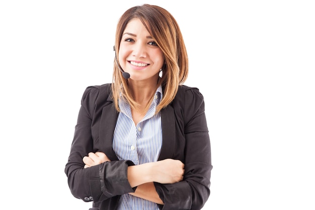 Portrait of a cute young Hispanic telemarketer wearing a headset and smiling on a white background