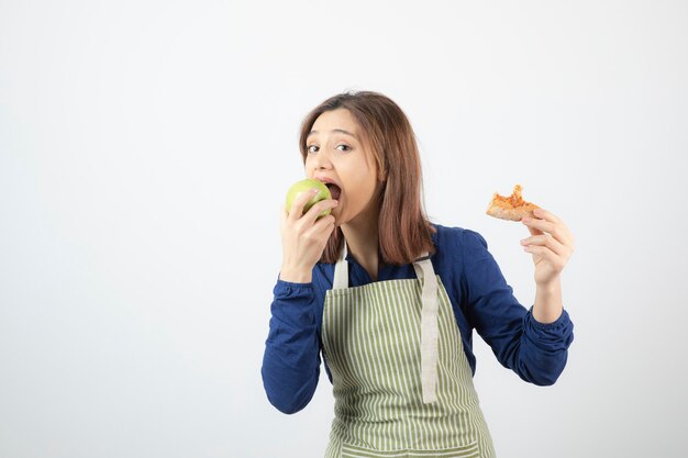 新鮮な青リンゴを食べるエプロンでかわいい若い女性の肖像画。