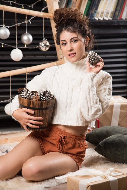 Portrait of a cute young woman holding pinecones in her hands 