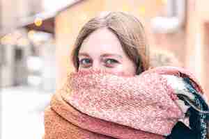 Free photo portrait of a cute young woman wrapped in a scarf in winter