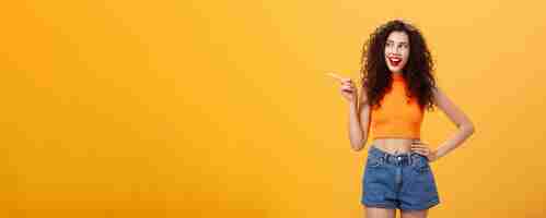 Free photo portrait of delighted enthusiastic stylish young woman with curly hairstyle in red lipstick and crop