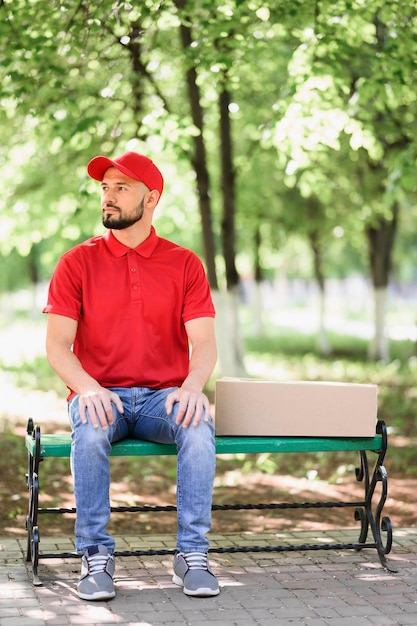 Free photo portrait of delivery man sitting on a bench