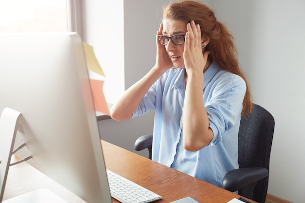 Foto gratuita ritratto di imprenditore femminile depresso seduto davanti al computer mentre si lavora in ufficio