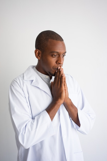 Free photo portrait of desperate black man in white coat praying.