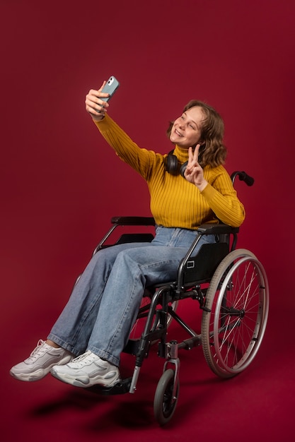 Foto gratuita ritratto di donna disabile su sedia a rotelle con smartphone